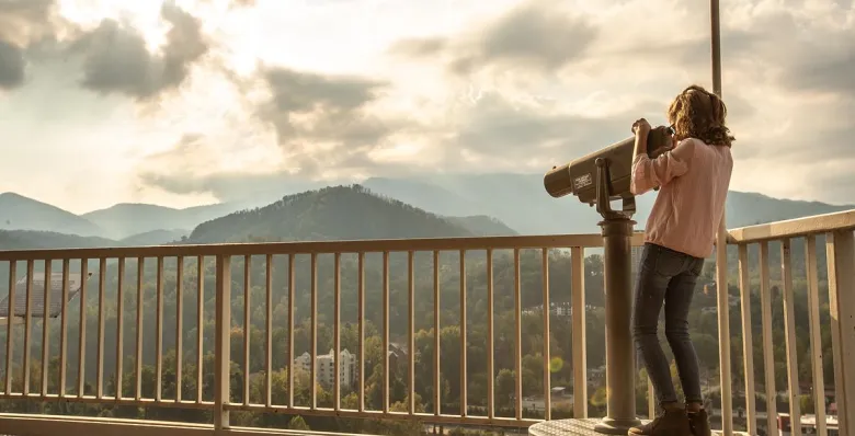 A child uses a telescope to view the mountains from the top of the Gatlinburg Space Needle at sunset.