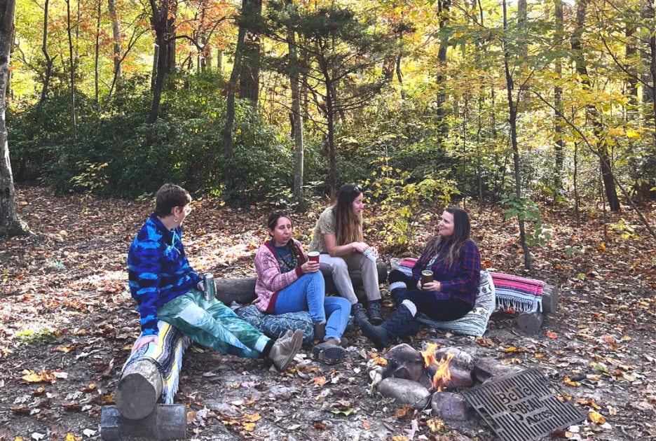 A group of women gathered around the fire during a fall campout at Belle and Beau Acres
